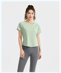 Woman wearing a light green athletic yoga t-shirt and grey high-waisted leggings set