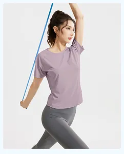 Detail of woman in purple sports t-shirt and grey leggings exercising with band