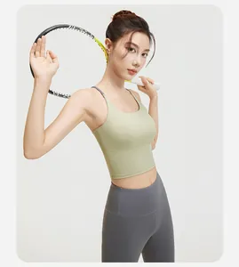 Model in groene sport-bh en grijze yoga-leggings met hoge taille en een tennisracket.