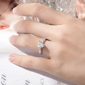 Nahaufnahme eines herzförmigen Moissanit-Rings am Finger, der Glanz und Details zeigt.
