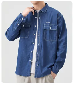 Dettaglio camicia in denim blu con cuciture bianche a contrasto e tasche sul petto