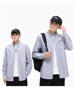 Modèle masculin portant une chemise en coton gris à manches longues sur un t-shirt blanc.