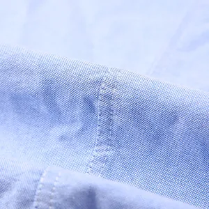 Détail macro d'une chemise à manches longues en pur coton bleu clair avec coutures