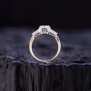 Detailweergave van stralend geslepen moissanite ring met taps toelopende baguette stenen.