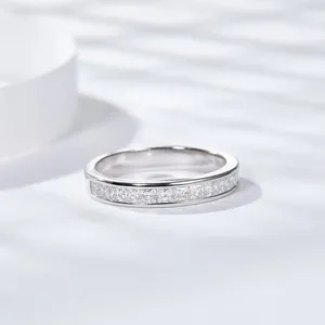 Plano detalle de un anillo de plata con moissanita de corte princesa y sombras.