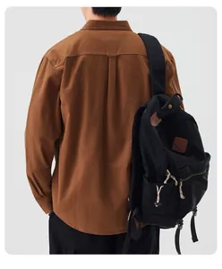 Rear view of a man wearing a brown casual long-sleeve shirt with a black backpack