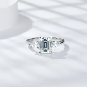 Primer plano de anillo de moissanita talla esmeralda con piedras laterales de pera