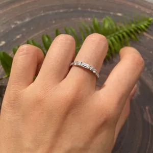 Detaillierte Nahaufnahme eines Baguette-Moissanit-Rings aus Silber an einer Hand mit Farn