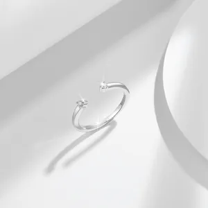 Primo piano di un anello aperto in argento S925 con due moissaniti in un ambiente bianco puro.