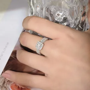 Primer plano de un brillante anillo de compromiso de moissanita corte princesa en una mano