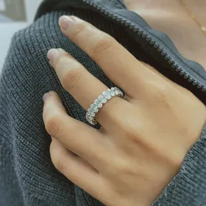 Detailed close-up view of an elegant oval-cut moissanite eternity ring on a hand.