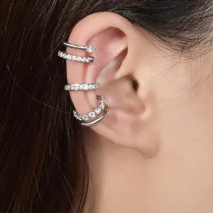 Primo piano di ear cuff a strati in argento S925 con moissanite su orecchio.