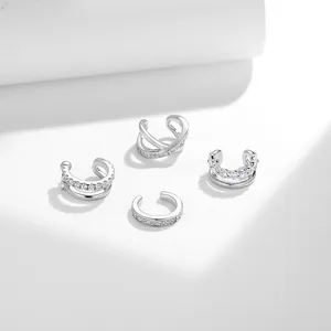 Vista dettagliata di quattro ear cuff argentati con accenti di moissanite in vari stili.