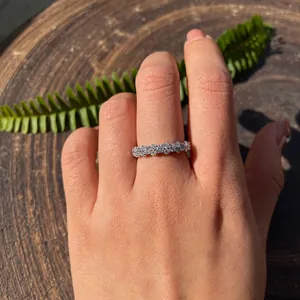 Primer plano de un anillo de moissanita brillante usado sobre fondo de madera.
