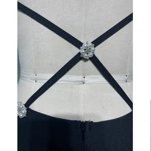 Dettaglio spalline incrociate con fibbie floreali in perla su abito a bende nero elegante.