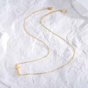 Vista detallada de un elegante collar con colgante de cruz de acero dorado sobre piedra blanca
