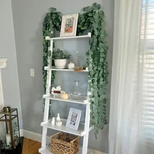 Artificial green eucalyptus garland draped on a white ladder shelf for home decor.