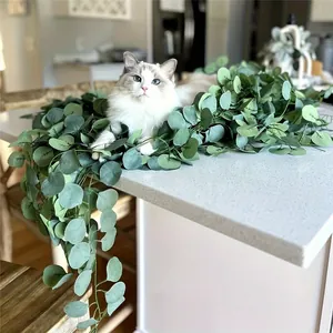 Close-up of realistic artificial eucalyptus garland on a white kitchen counter with a cat