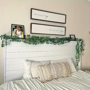 Lifelike artificial eucalyptus garland draped over a white rustic farmhouse headboard