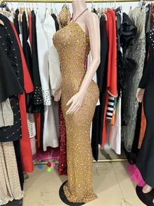 Side view of luxury sparkling gold rhinestone mesh backless long evening dress on mannequin.