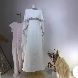 Elegant white long dress featuring intricate rhinestone embroidery on the neckline and cape