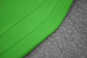 Macro detail of the vibrant green ribbed fabric and neat double-stitching on a dress.