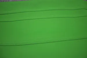 Detailed macro view showing the green ribbed bandage fabric texture on a sexy bodycon dress