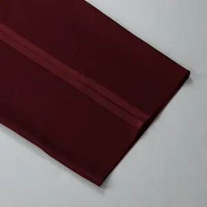 Macro view showing the thick bandage fabric texture and seam of the burgundy dress.