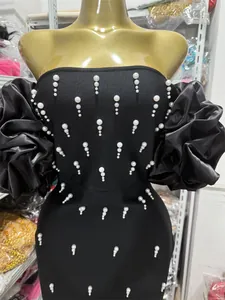 Detailed view of an elegant black off-the-shoulder bandage dress with pearl decorations