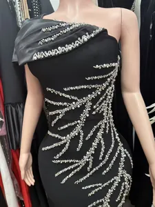 Detailed view of black one-shoulder bandage dress with pearl and silver bead embellishments