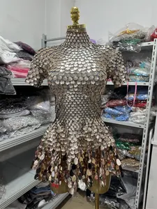 Dettaglio di un luccicante abito da festa con paillettes dorate esposto su un manichino