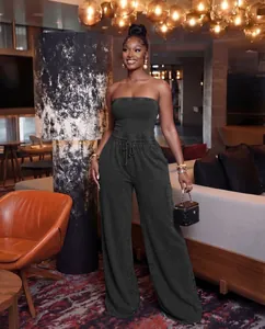 Elegant washed black strapless wide-leg jumpsuit modeled in a luxury lounge setting.