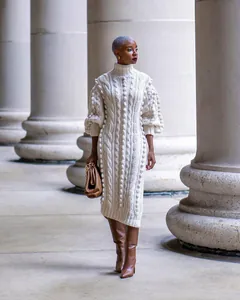 Detailed view of a white chunky cable-knit turtleneck sweater dress on a model