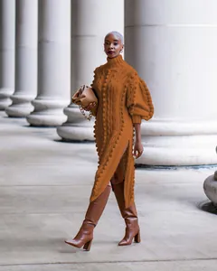 Elegant brown chunky knit long dress with high neck and side split shown on model.