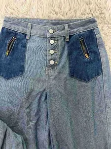 Close-up of patchwork denim jeans featuring multi-button fly and zipper pocket details.