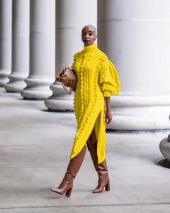 Detailed view of yellow cable knit maxi dress featuring pom-pom texture and high side slit