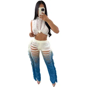 Woman wearing a stylish white distressed crop top and blue ombre shredded fringe pants