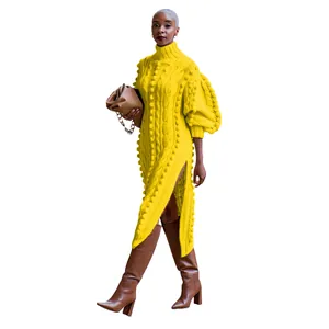 Close-up of vibrant yellow high-neck knit maxi dress featuring side split and pom-pom texture.