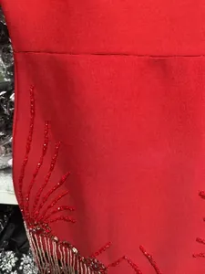 Detailed macro view showing red sequin embroidery and tassel fringe on a bandage dress