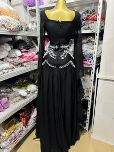 Rear view of black long-sleeved evening dress with intricate pearl beadwork at waist.