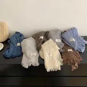 Collection of solid color pleated cotton linen scarves with decorative fringe details.