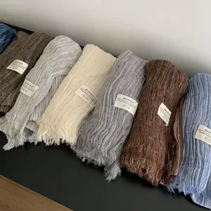 Close-up of long pleated cotton linen scarves in various elegant solid earth tones