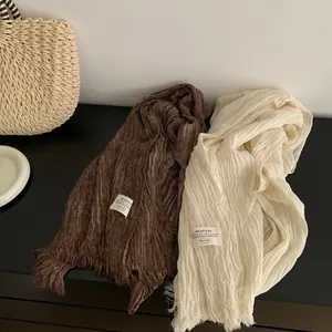 Detail of pleated cotton linen scarf with fringe in brown and cream white colors