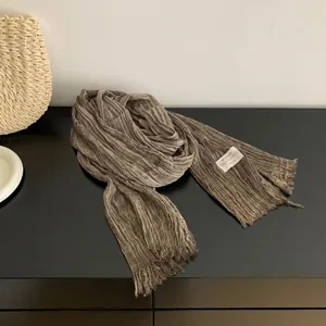 Detail shot of solid color pleated cotton linen scarf with fringe and brand tag.