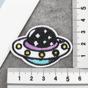 Macroweergave van geborduurde UFO-strijkpatch met linialen die 5x4 cm afmeting tonen.