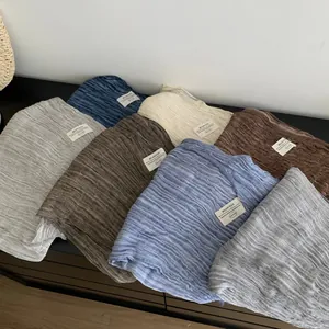 Solid color pleated cotton linen scarves in various shades displayed on a dark surface