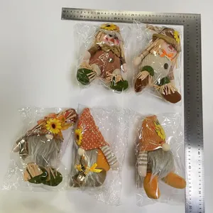 Five harvest-themed scarecrow gnomes measured with a ruler for size reference