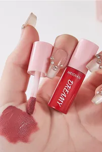 Close-up of MEIDIAN lip glaze swatch on hand with flocked applicator and pink tube.