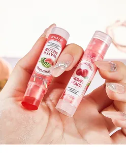 Close-up of Bosuya Watermelon and Honey Peach lip balms held in hand with glitter nails