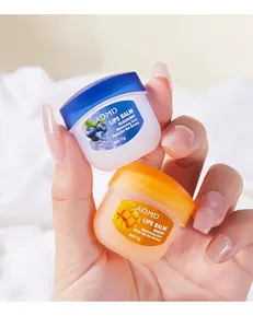 Nahaufnahme von ADMD Heidelbeer- und Mango-Lippenbalsam-Mini-Tiegeln in gepflegter Hand